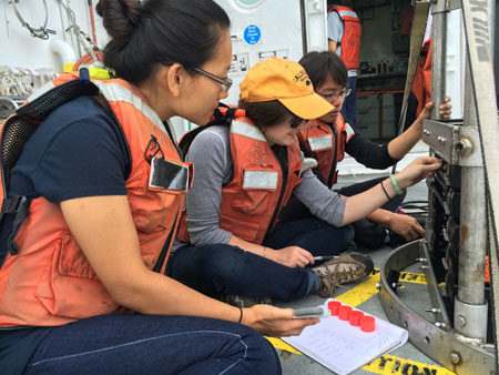 UC Berkeley students Xiao Fu, Hannah Bourne and YiZhuang Liu check the sensors on the CTD Rosette before the device's first launch off the Oceanus. (Credit: Sarah Yang) 